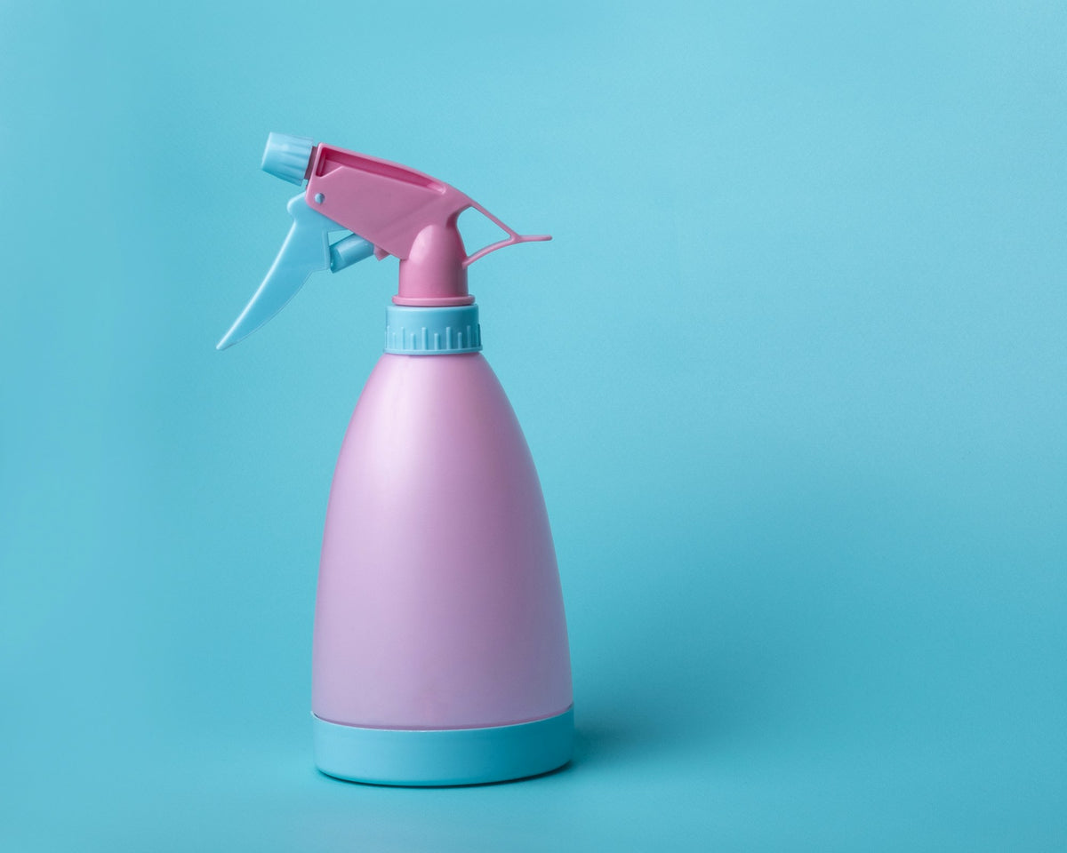Sprühflasche für Reinigungsmittel vor blauem Hintergrund
